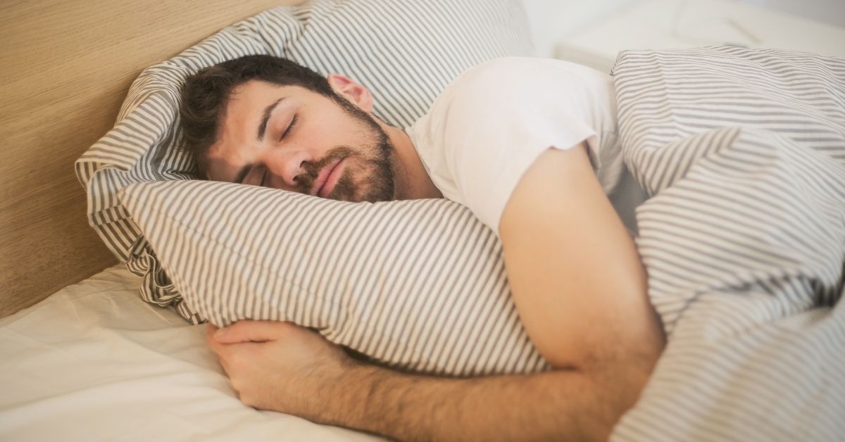 White man with beard snuggled up in bed